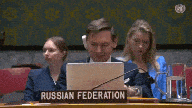 a man sitting in front of a laptop with a sign that says russian federation