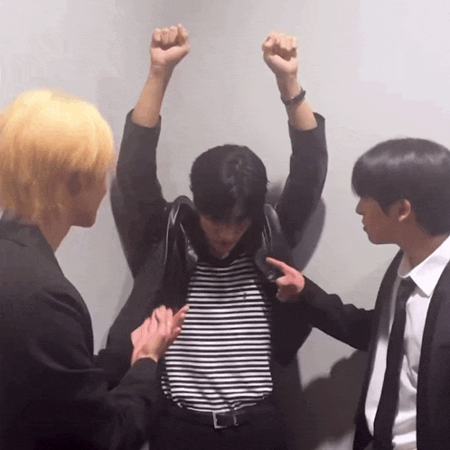 a man in a striped shirt is being helped by two other men in suits