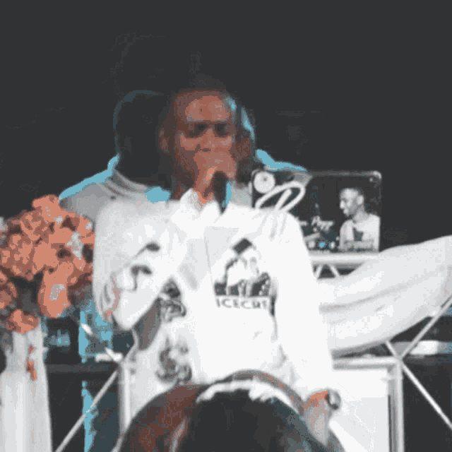 a man singing into a microphone while wearing a sweatshirt that says icecat