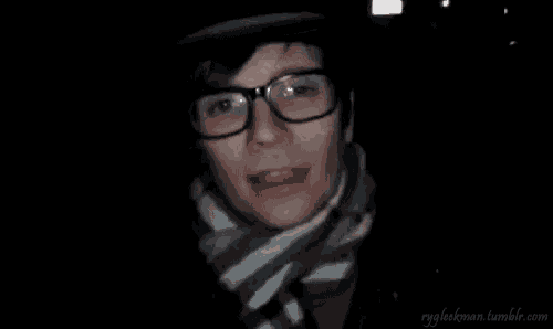 a man wearing glasses , a scarf and a hat is looking at the camera .