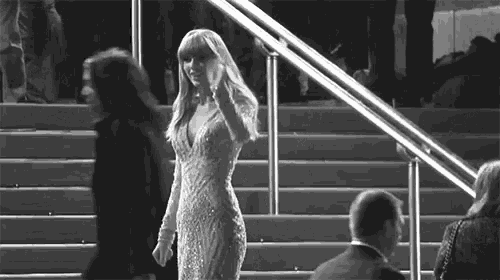 a woman in a dress is walking down a set of stairs in a black and white photo .