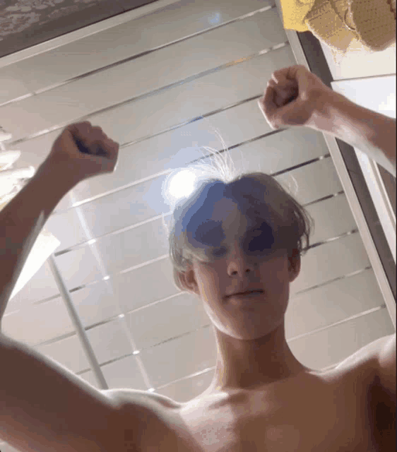 a shirtless young man flexes his muscles in front of a mirror