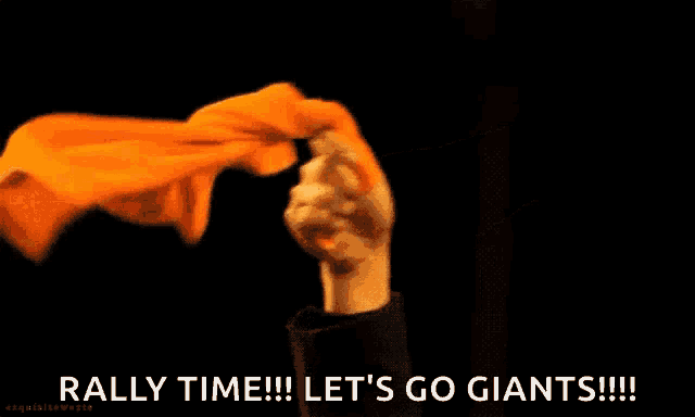 a person holding an orange cloth that says rally time let 's go giants !!!