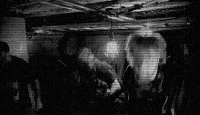 a black and white photo of a group of people standing in a room .