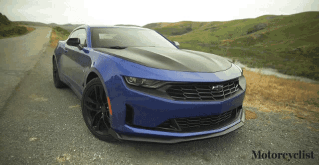 a blue sports car is parked on the side of a road with motorcyclist written on the bottom