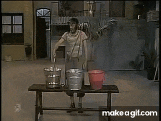 a man is standing on a wooden bench with three buckets on it .