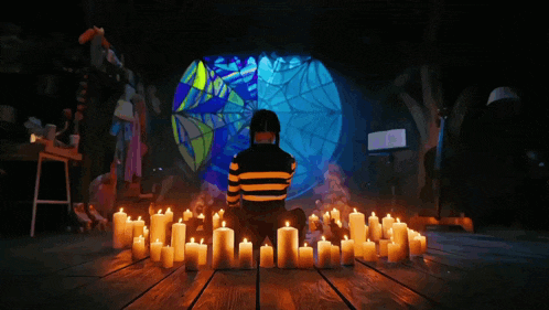 a person sitting in front of a stained glass window with candles