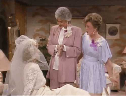 a woman in a purple suit stands next to a woman in a white dress