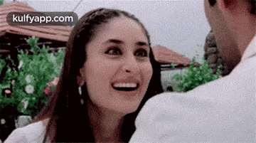a woman is smiling and looking at a man in a white shirt .