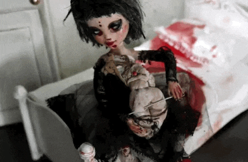 a creepy doll is sitting on top of a bloody bed holding a knife .