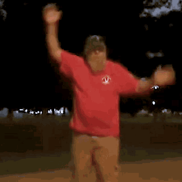 a man wearing a red shirt with a red circle on it is dancing