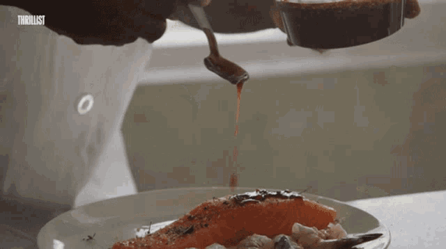 a close up of a person pouring sauce on a plate with thriller written in the upper right corner