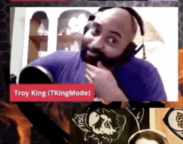 a man with a beard is wearing headphones and has a red sign that says troy king