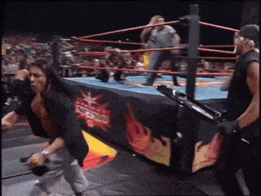 a man is standing in a wrestling ring holding a microphone and a gun .