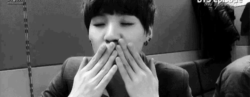 a young man is covering his mouth with his hands .