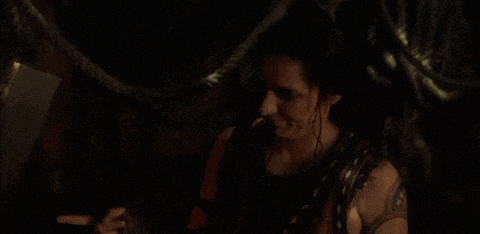 a woman is sitting in a dark room with a rope around her neck and a ring on her finger .