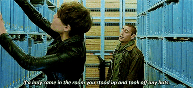 a man and a woman are standing in a library and the woman says if a lady come in the room