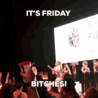 a group of people are standing in front of a large screen that says it 's friday bitches !