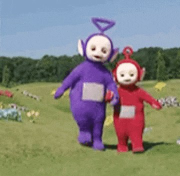two teletubbies , purple and red , are walking in a grassy field .