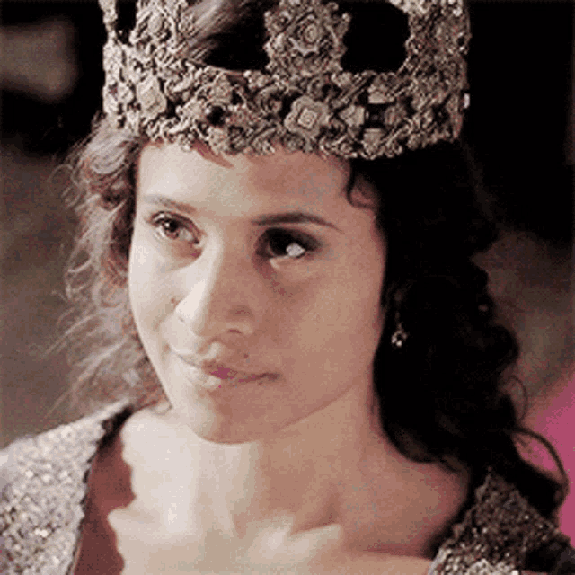 a woman wearing a crown is smiling and looking at the camera
