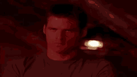 a close up of a man 's face in a dark room with a red light shining on it .