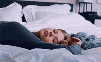 a woman is laying on a bed with her eyes closed and her mouth open .