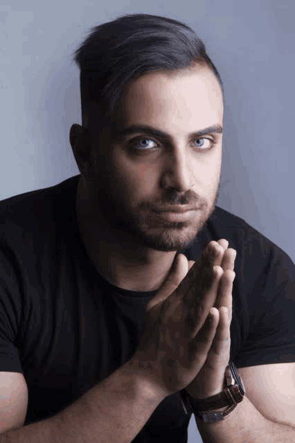 a man in a black shirt with his hands folded