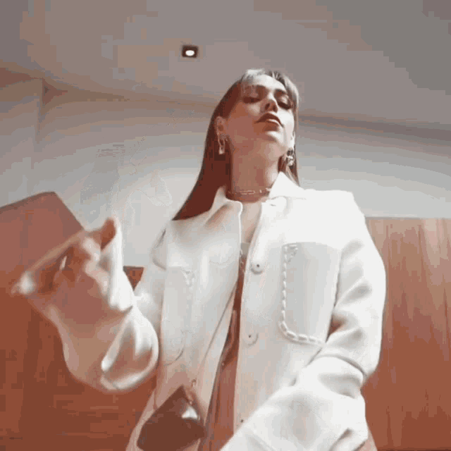 a woman is wearing a white jacket and a black bag