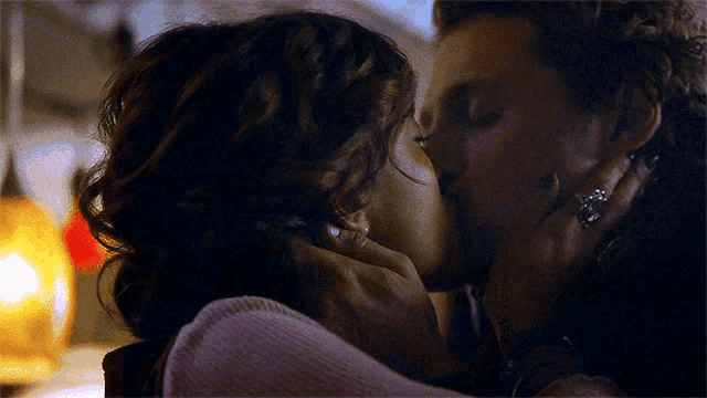 a man and a woman are kissing in a room