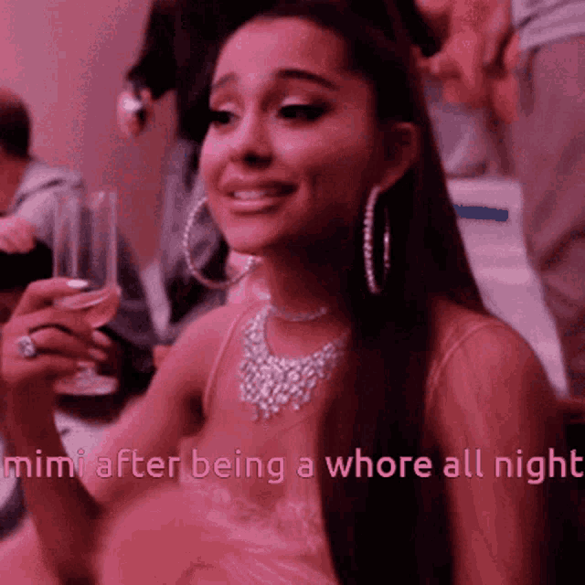 a woman in a pink dress is holding a glass of wine in her hand .