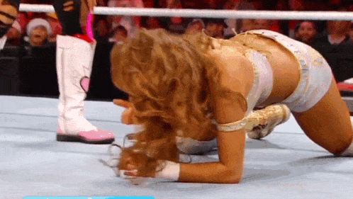 a female wrestler is kneeling on the floor in a ring