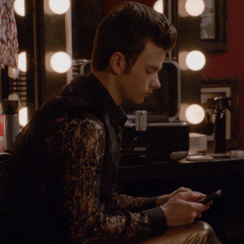 a man sitting in front of a mirror looking at his cell phone