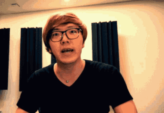 a young man wearing glasses and a black shirt is making a face