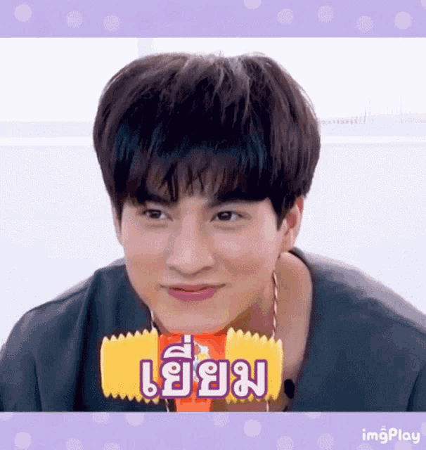 a young man is holding a candy bar in his mouth and making a face .