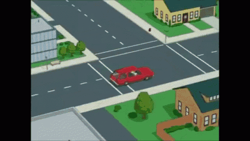 a red car is driving through an intersection with a yellow house in the background