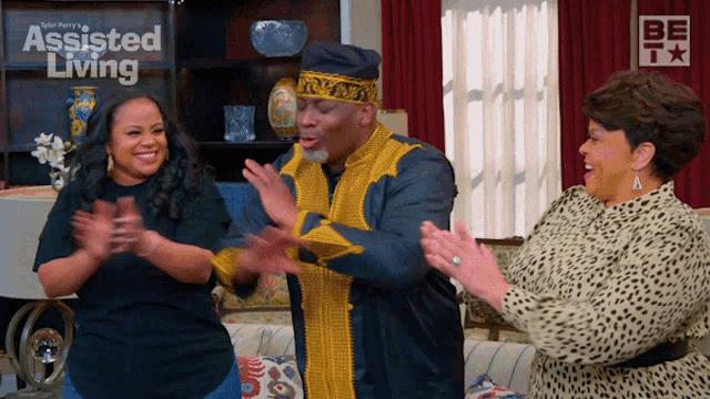 three people are clapping in front of a sign that says assisted living on it