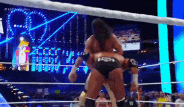 two men are wrestling in a wrestling ring with a crowd in the background .