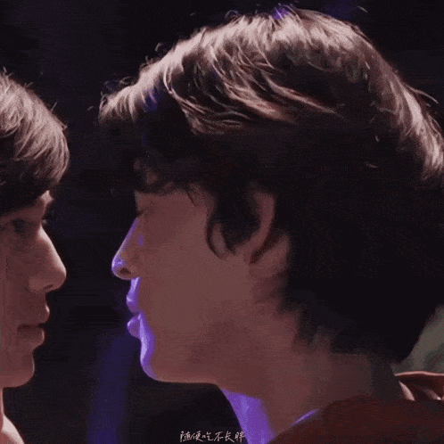 a close up of a man kissing another man with chinese writing on it