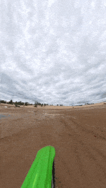 a person riding a dirt bike on a dirt road with a cloudy sky in the background