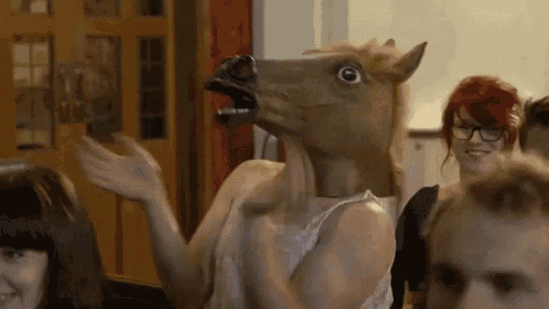 a woman wearing a horse mask is waving at a group of people .