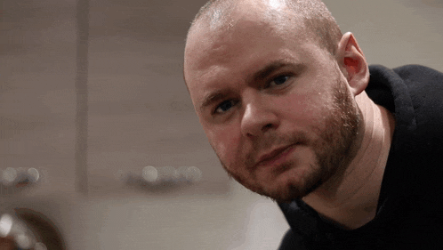 a man with a beard and a black shirt looks at the camera