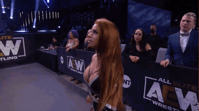 a woman stands in front of a wall that says aw wrestling