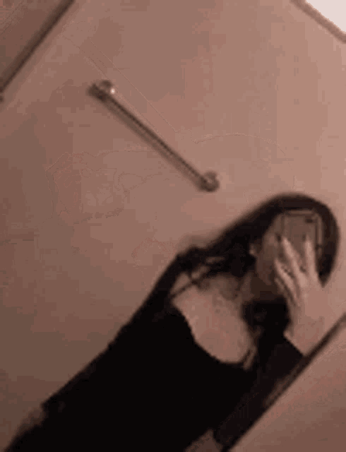 a woman is taking a picture of herself in a bathroom mirror .