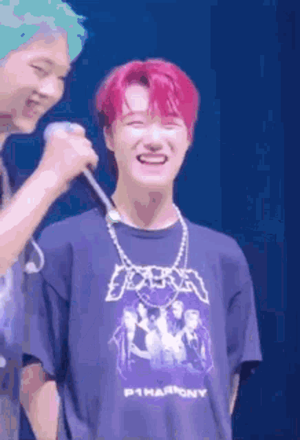 a man with red hair is holding a microphone next to another man .