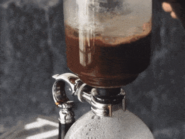 a close up of a coffee maker with bubbles on the top