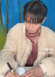 a person wearing a fur coat is writing on a piece of paper .