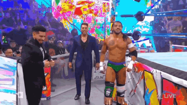 a group of men are standing in a wrestling ring talking to each other .