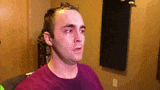 a man in a red shirt is sitting in a room with his eyes closed and a tear running down his face .