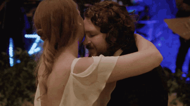 a bride and groom are hugging and kissing in front of a sign that says 7