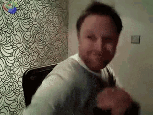 a man is making a funny face in front of a wall with a banana pattern .